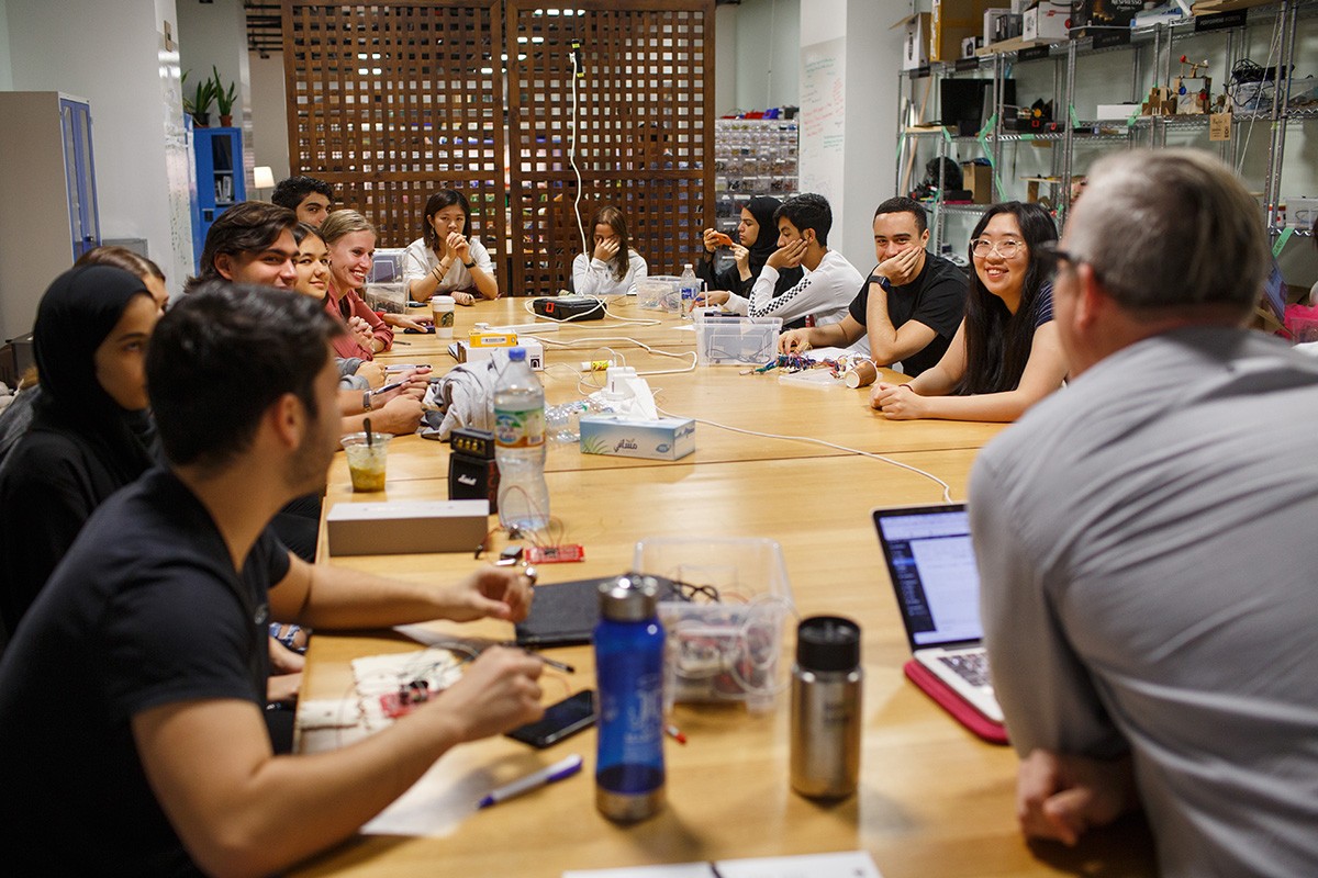 NYUAD students and professor sit around a table in an Arts and Humanities classroom.