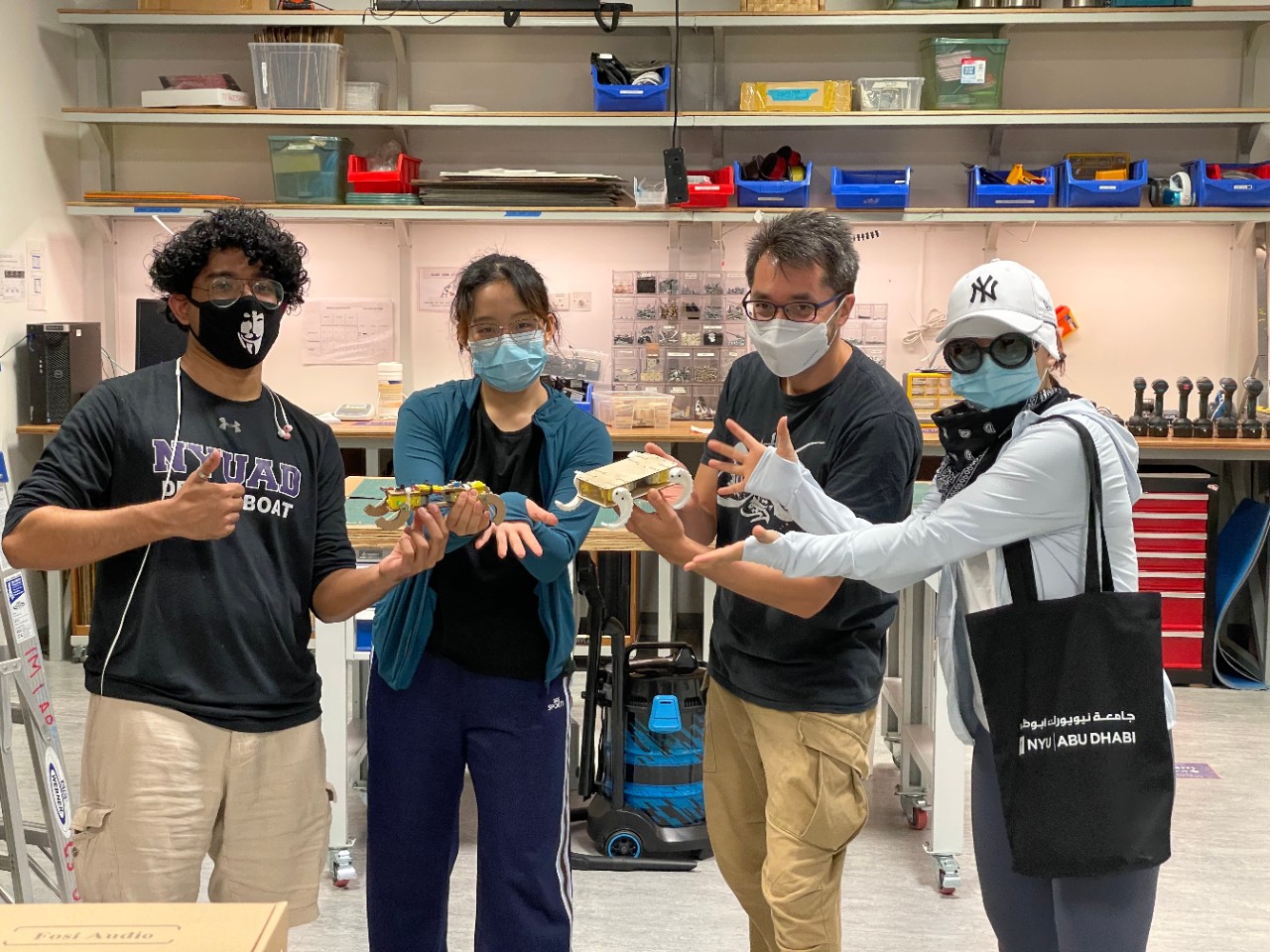 Lydia Yan, fall 2021 Undergraduate Research Assistantship award recipient, standing alongside Professor Ang and fellow students, showcasing prototype robots they created for the Interactive Media department.
