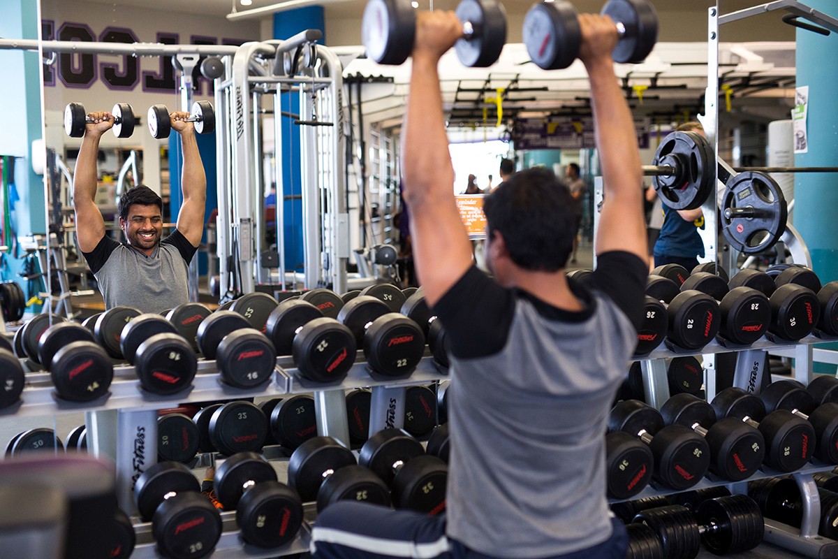A gym user lifting weights in the fitness center on campus. 