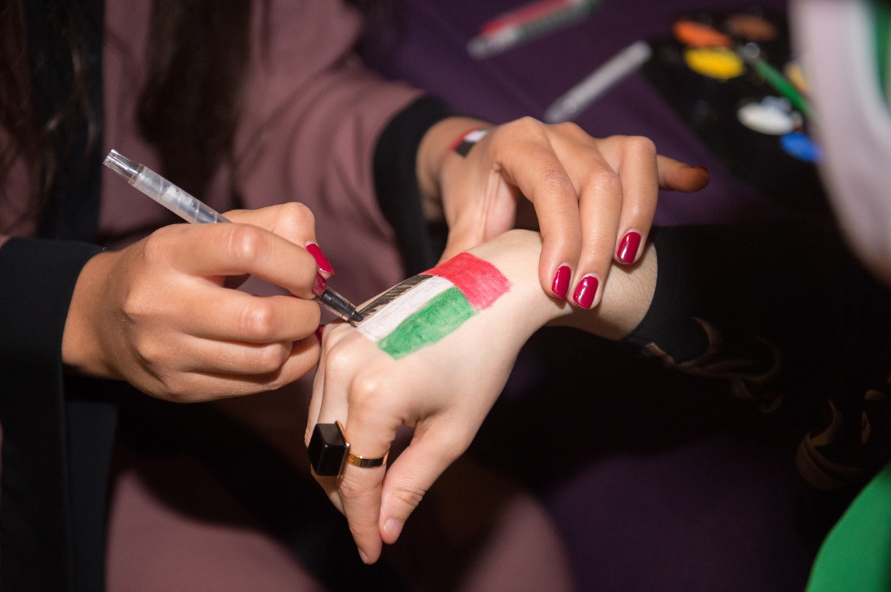 Drawing of the UAE flag on the hand of a lady.
