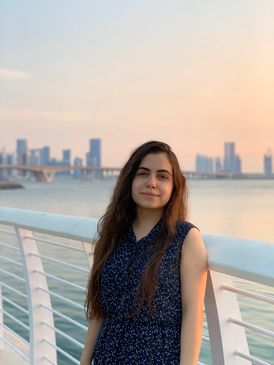 Milena Baghdasaryan, leans against the handrail on the Corniche, at sunset.