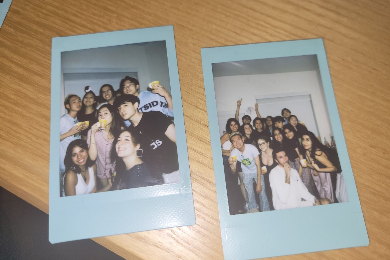 Photos of NYUAD Class of 2024 in two polaroid photos on the table. 