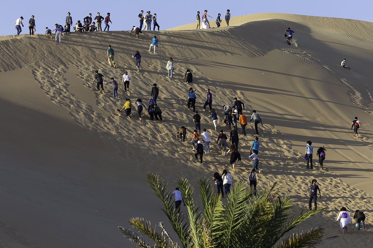 Students climb a sand dune in the UAE desert.