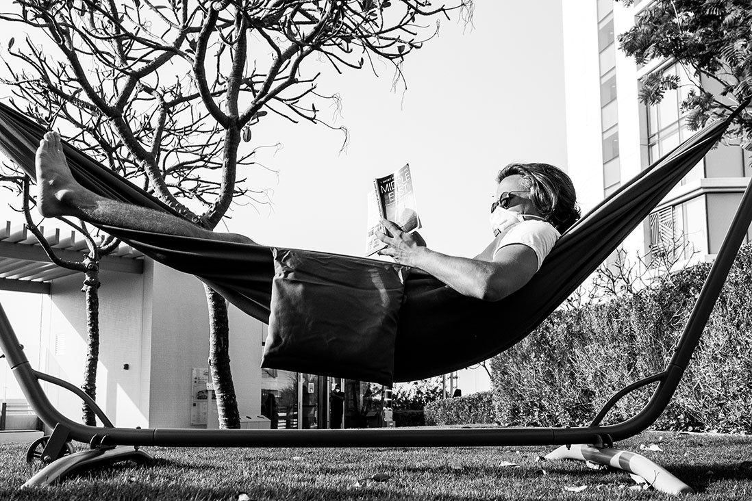 A student wears a mask while enjoying some sun in a hammock on campus. Image by @abelerphotos