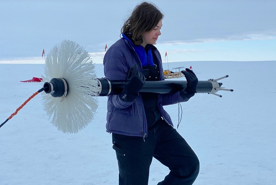NYU graduate student Aurora Basinski carries a turbulence measuring device to the borehole on Thwaites Glacier