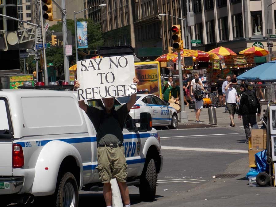 A man holds a 'Say No to Refugees' sign at Columbus Circle in New York City.