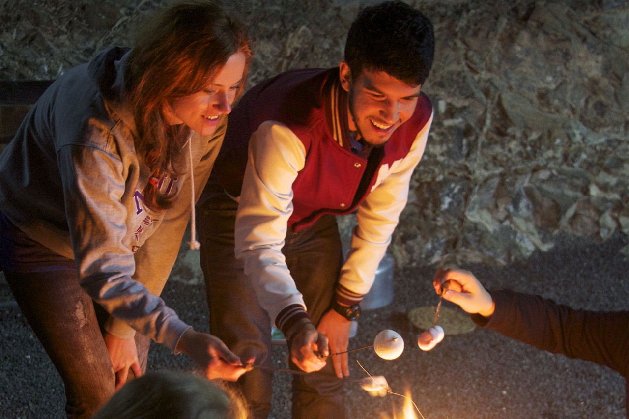 Students roasting marshmallows over a bonfire.