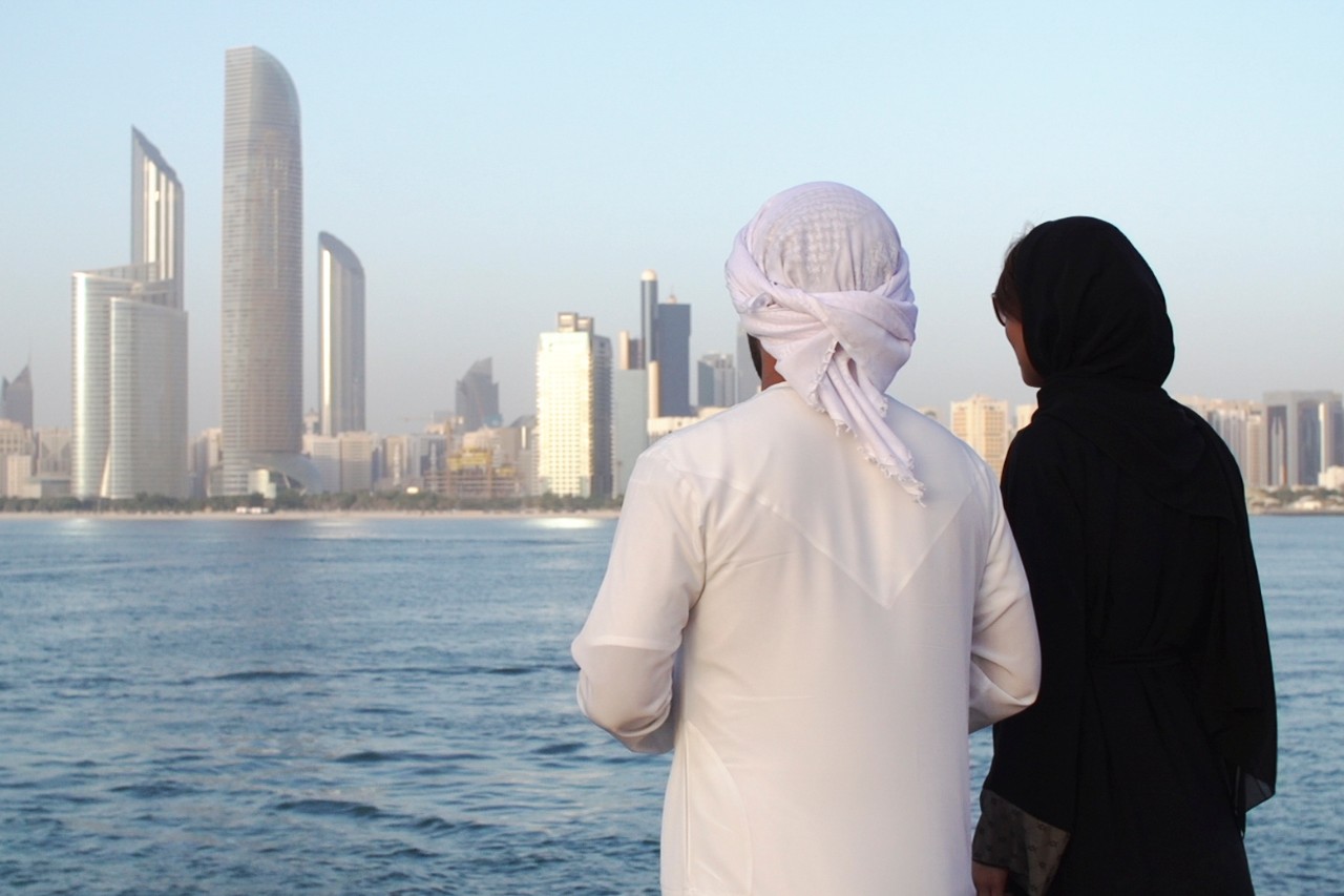 Emirati man and woman standing along the corniche.