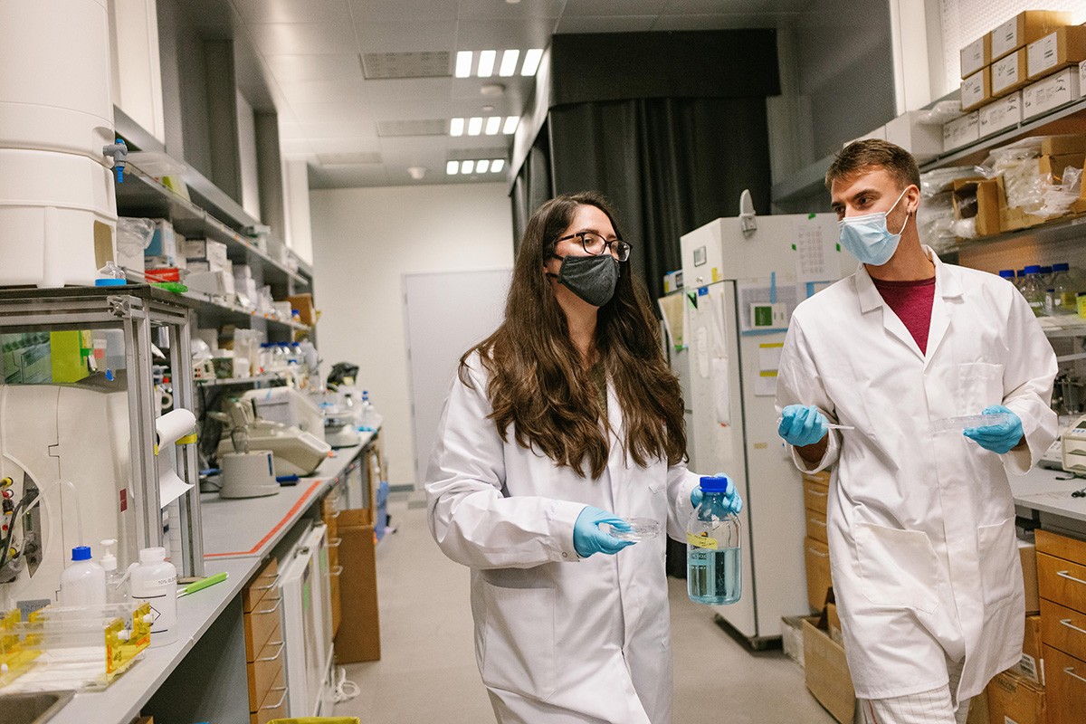 Two students walking in a chemistry lab at NYUAD, holding samples.
